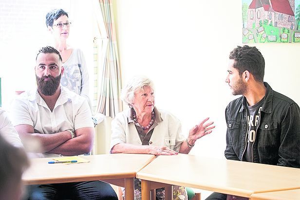 Fragestunde: Übersetzer Ali (rechts) unterstützt bei der Kommunikation zwischen einer Patin aus der Kirchengemeinde (Mitte) und den in Rammelsloh getauften Flüchtlingen.