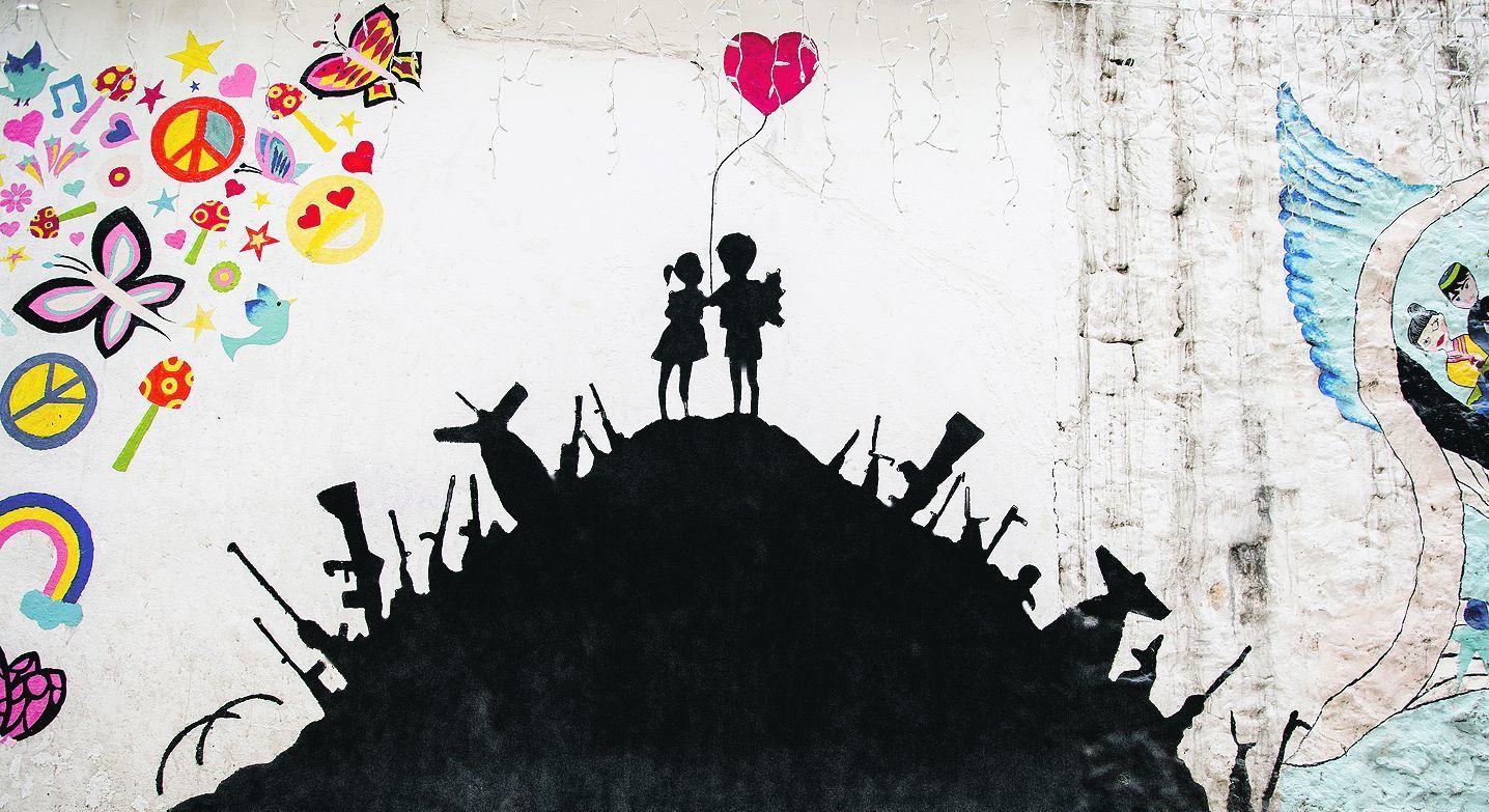 Friedenssehnsucht: Dieses Graffito an einer Schule in Hasaka im Nordosten Syriens zeigt in einem Erdhaufen steckende Waffen und oben Kinder mit einem roten Herz-Luftballon.