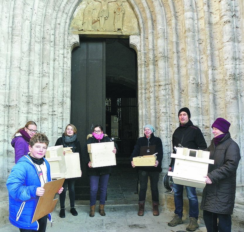 Gemeindemitglieder mit Nistkästen vor der Kirche.