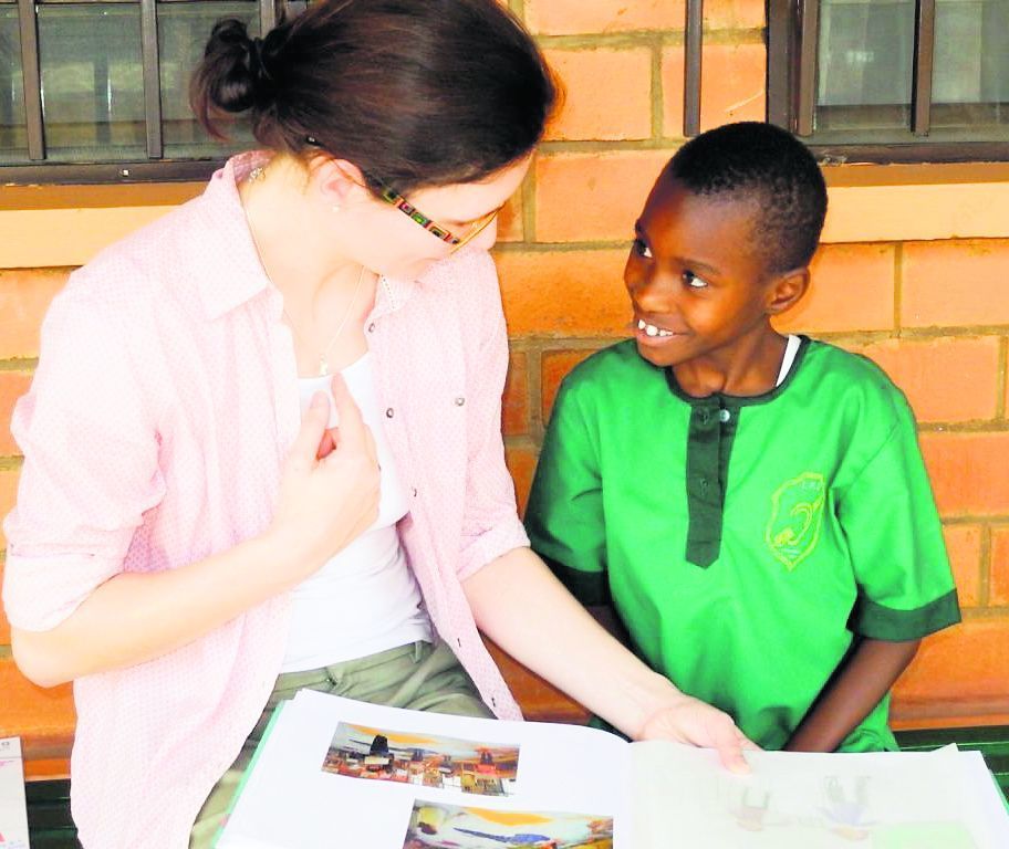 Manja Güldenpfennig betrachtet mit Dina, dem Patenkind der Evangelischen Grundschule in Eisenach, ein von ihren Schülern gestaltetes Fotobuch.
