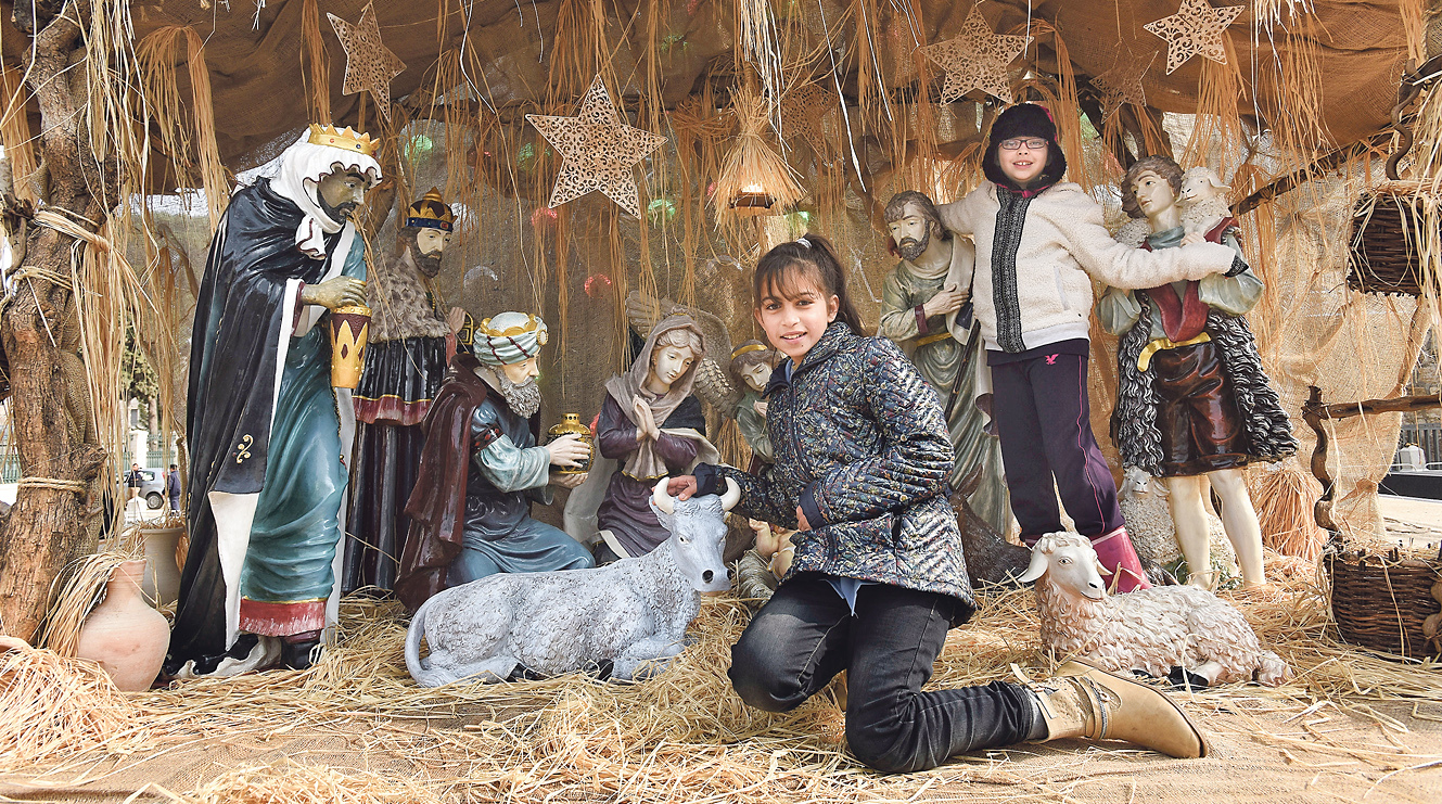 Legende: Die Futterkrippe wird bei Lukas erwähnt. Von Ochs und Esel ist nicht die Rede. Mädchen aus Jordanien (Foto) im Dezember 2015 in der Krippenszene auf dem Manger-Platz in Bethlehem, neben der Geburtskirche. In Bethlehem ist die Vorweihnachtszeit die wichtigste für das Geschäft mit den Touristen.