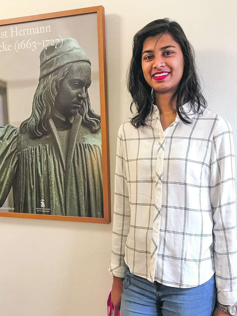Jasmin Issakiraja vor einem Plakat mit dem Bild August Hermann Franckes.