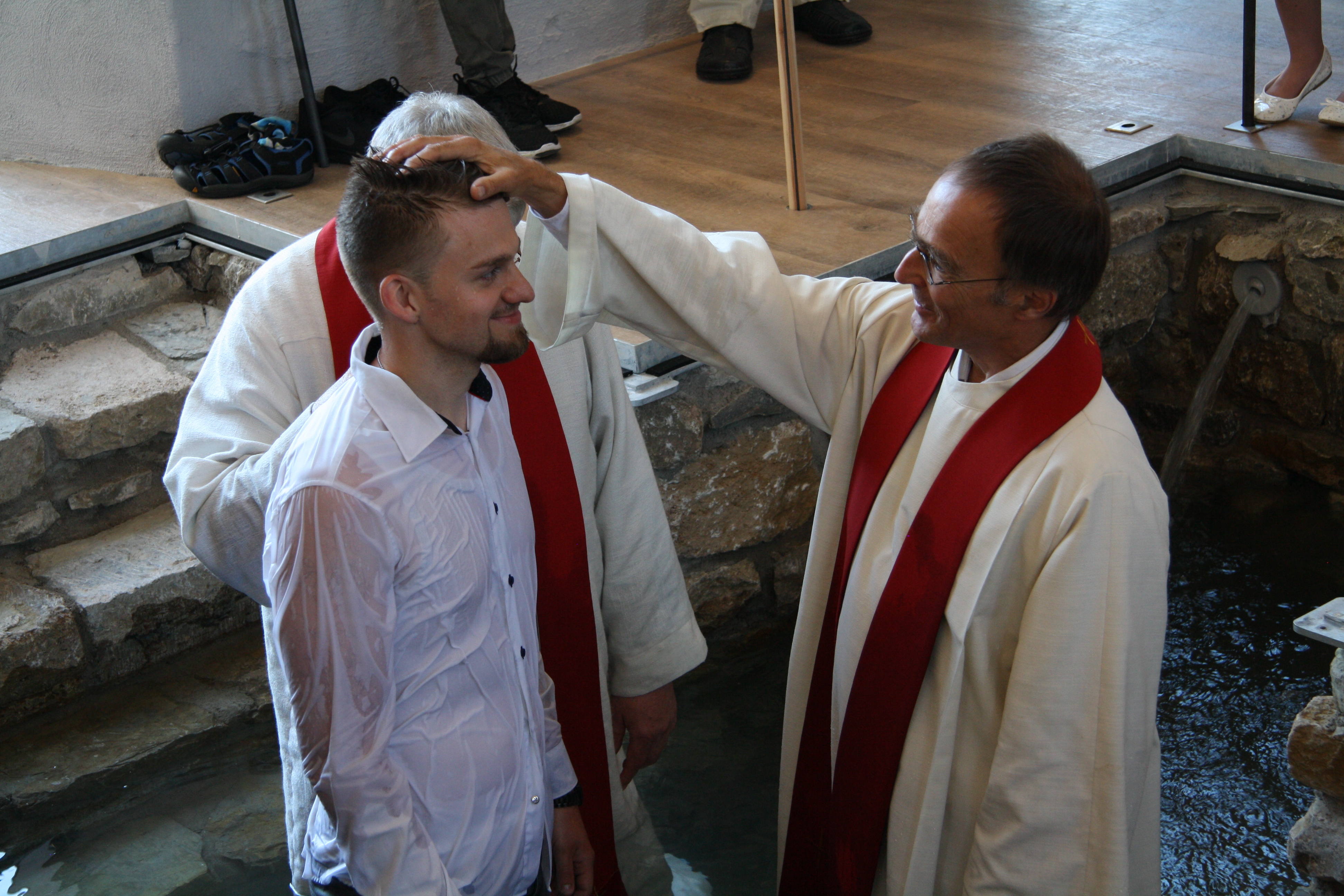 Pfarrer Christian Schaube (r.) bei einer Erwachsenentaufe im Baptisterium .