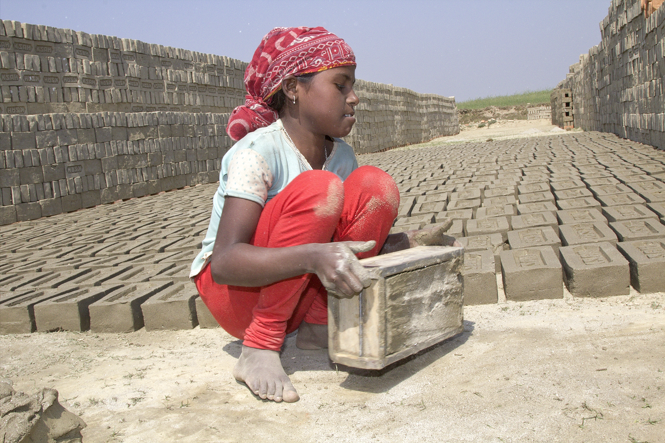 Ein Mädchen stellt in einer Ziegelei in Indien Lehmziegel her. Die Kindernothilfe setzt sich für die Kinder ein.