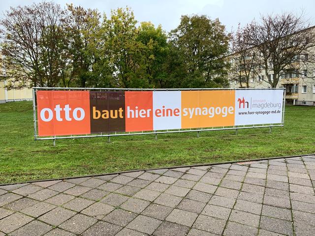 Ein neues Banner macht auf den geplanten Bau der Synagoge aufmerksam.