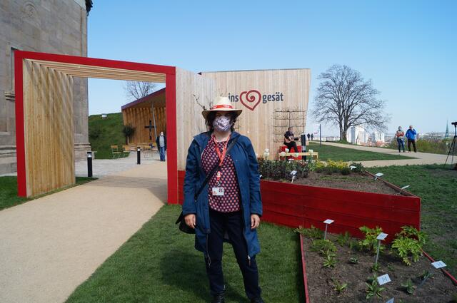 Marion Müller ist die Ansprechpartnerin der Kirchenpräsenz auf dem Petersberg. Auf dem Hochbeet dahinter wachsen neben roten und weißen Tulpen auch verschiedene Heilkräuter.