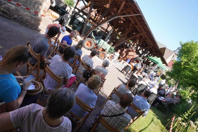Gottesdienstbesucher auf dem Freigelände des Börde-Museums in Ummendorf. Im Hintergrund: historische landwirtschaftliche Nutzfahrzeuge.