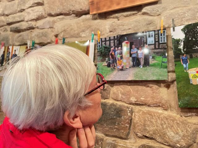 Eine Betrachterin vor einem Foto der Friedensaktivisten mit der originalen Litfaßsäule aus Pappe, das im "Roten Loch" gezeigt wurde.

 | Foto: Sabine Bujack