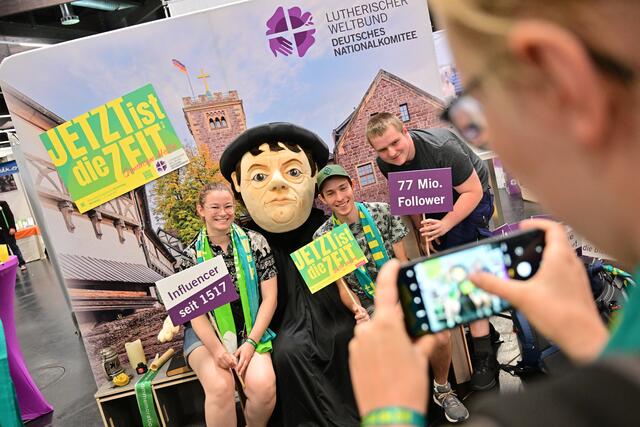 Kirchentagsbesucher lassen sich am Stand des Lutherischen Weltbunds beim Markt der Möglichkeiten in der Messehalle mit einer großen Luther-Puppe fotografieren | Foto:  epd-bild/Thomas Lohnes