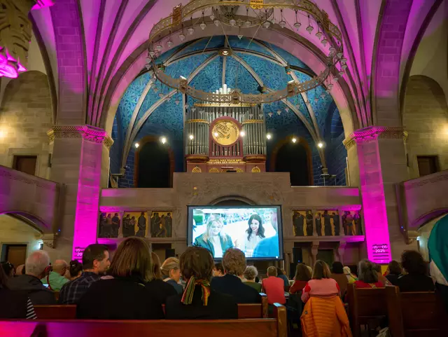 ESC Public Viewing: Im Rundbau der Pauluskirche in Basel erklingt das "Te Deum" von Marc-Antoine Charpentier. Die bekannte Eurovisions-Hymne breitet sich in der Kirche von 1901 aus und lässt die Pfeifen der Jugendstil-Orgel mitschwingen. Die Leinwand vor dem ehemaligen Altar zeigt die grosse Bühne des 69. Eurovision Song Contest (ESC) in der St. Jakobshalle in Basel. | Foto: epd-bild/Christine Siefer