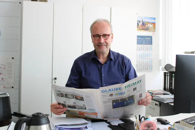 Kirchenzeitungsleser Marc Rath in seinem Büro. Am liebsten liest er "Glaube + Heimat" am Wochenende. Das sei sein ganz persönlicher Gottesdienst, sagt er. | Foto: Oliver Gierens