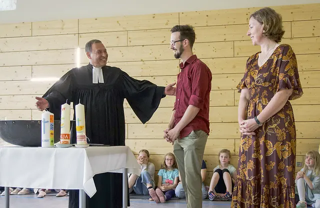 Franz Hanke (M.), Erzieher an der Evangelischen Grundschule Halle, wird von Ekkehard Steinhäuser getauft. Als Taufpatin mit dabei ist Elisabeth Lauterbach. | Foto: Evangelische Grundschule Halle/Christian Hentschel