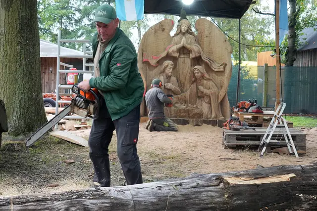 Christian Seliger bereitet Holz für die Künstler vor. Im Hintergrund entsteht das Relief „Ein Engel behütet Maria und Josef mit dem Kind“.  | Foto: Wolfgang Hesse