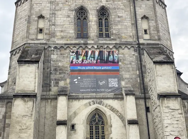 Die Evangelische Hochschule für Kirchenmusik Halle blickt in diesem Jahr auf ihre 100-jährige Geschichte zurück. Darauf macht auch ein Banner an der Marktkirche aufmerksam. | Foto: Foto: Claudia Crodel
