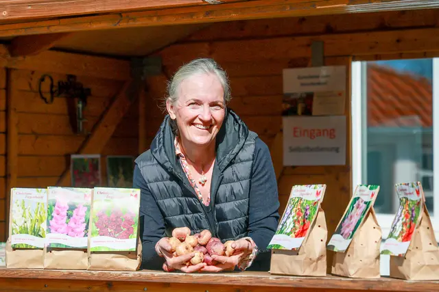 Christiane Degenhardt vom Gartenbaubetrieb Degenhardt in ihrem Verkaufstand in Schwaneberg vor den Toren Magdeburgs. Sie zeigt Gladiolenzwiebeln.  | Foto: epd-bild/Viktoria Kuehne