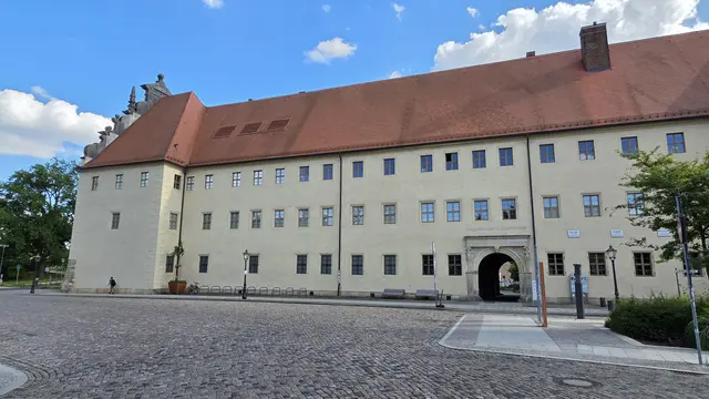Straßenansicht des Augusteums, in welchem bis zum Herbst 2027 die Interimsausstellung zu Martin Luther untergebracht ist. Der historische Durchgang (rechts) führt auf den Hof des Lutherhauses mit der berühmten Lutherlinde und dem Eingangsportal für den Neubau. | Foto: Thomas Nawrath