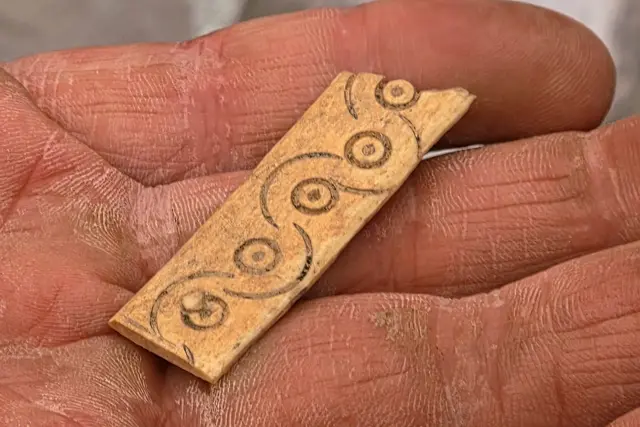 Plättchen (wohl aus Geweih oder Knochen) mit Kreisaugen-Verzierungen.