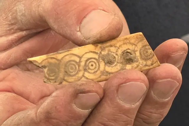 Plättchen (wohl aus Geweih oder Knochen) mit kunstvollen Kreisaugen-Verzierungen.