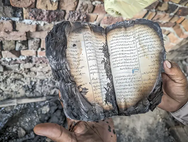 Immer wieder kommt es zu Anschlägen auf christliche Kirchen in Pakistan, so wie im August 2023 in Jaranwala in der Provinz Punjab. Ein Mann hält die verkohlten Reste einer Bibel in urdischer Sprache.
