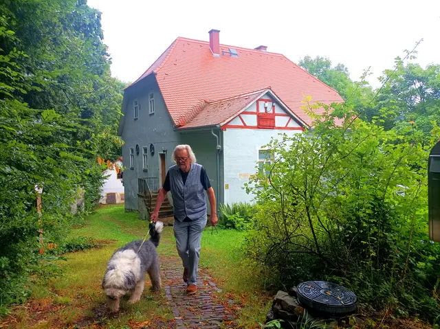 Stiftungsvorstand Jochen Süss mit Hund Sir Winston vor dem Brehm-Pfarrhaus in Renthendorf, Ostthüringen (Foto vom 23.07.2025). Das historische Gebäude vervollständigt das benachbarte Museum. | Foto: epd-bild/Matthias Thüsing