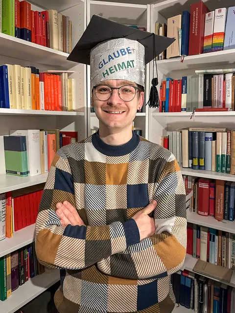 Chapeau! Der Thüringer Diplomtheologe Karl-Christoph Goldammer promovierte "summa cum laude" (mit höchstem Lob) mit seiner Doktorarbeit "Kirchliche Publizistik in der DDR. Die Kirchenzeitung Glaube und Heimat zwischen 1946 und 1990". Gutachter seiner mehr als 600 Seiten umfassenden Dissertation waren die Professoren Christopher Spehr und Michael Wermke. Die Theologische Fakultät der Universität Jena verlieh Goldammer nun den Doktorgrad der Theologie. Ehefrau Esther kreierte den originellen Doktorhut. Die Redaktion von "Glaube + Heimat" gratuliert Doktor Goldammer und wünscht ein segensreiches Wirken im Vikariat! Goldammer hat sich bereits im Buch "Evangelische Publizistik – wohin?" in einem Beitrag mit der Geschichte der Kirchenzeitung beschäftigt. 

Rezension und Bestellinfos:
t1p.de/evangelische-publizistik | Foto: Esther Goldammer